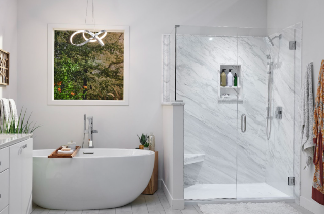 Modern bathroom with a freestanding soaking tub, marble walk-in shower, and large window with a view of greenery outside. | Re-Bath