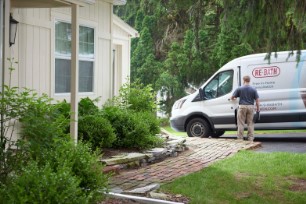 A Re-Bath employee steps into the driver's seat of a branded van parked in the driveway of a suburban home. | Re-Bath